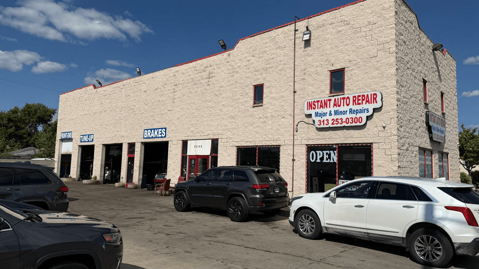 The Instant Auto Repair building on W Warren Avenue in Detroit, with the red and white sign, the phone number and the open service bays